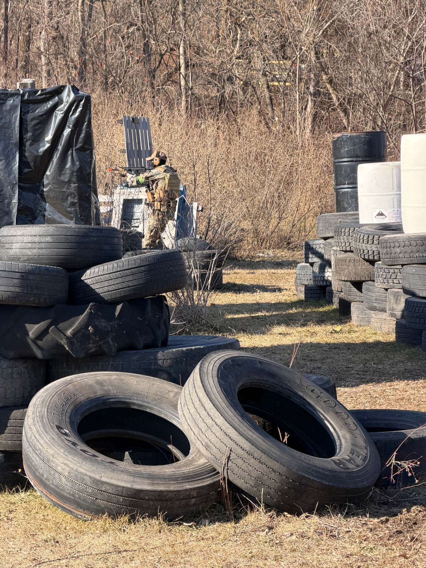 A player in tactical gear waits behind a wall of stacked vehicle tyres on the Korhaven field